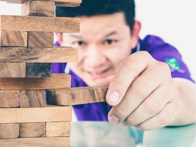 asian guy is playing a wood blocks tower game for practicing physical and mental skill