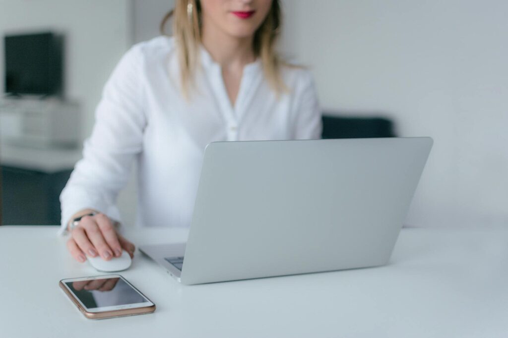 A woman multitasking with a laptop and phone to address cybersecurity threats.