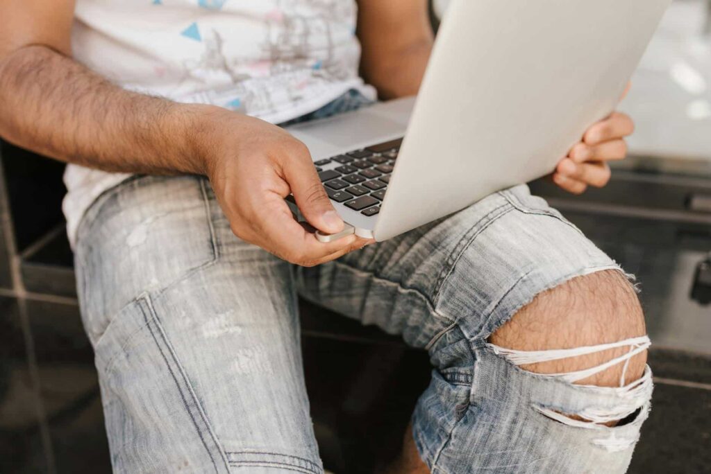 A man sitting on a bench with a laptop researching IT.