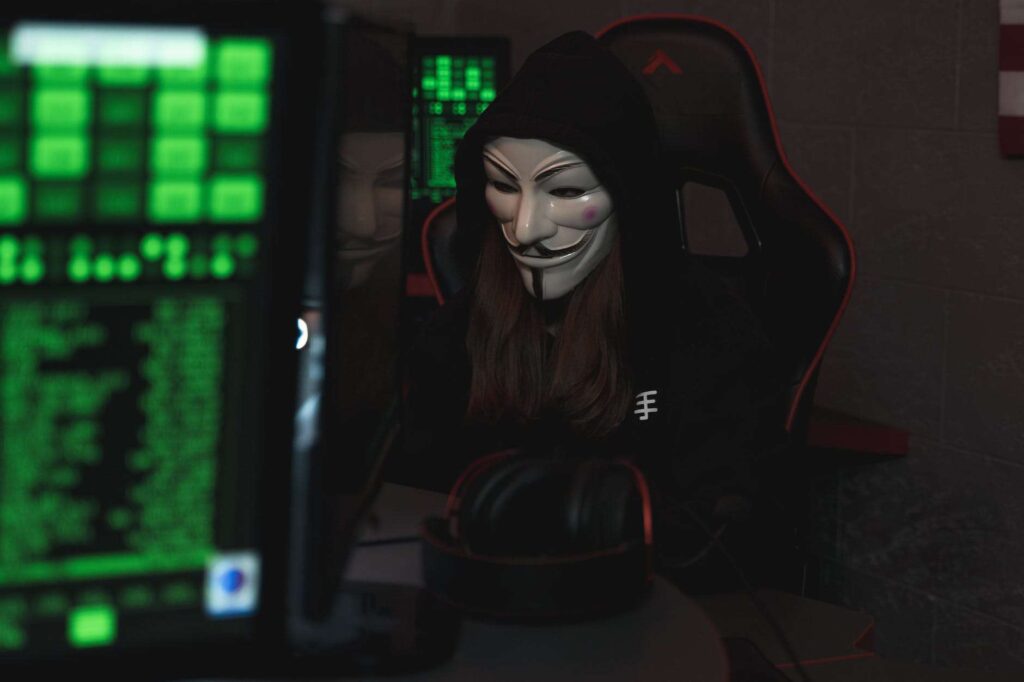 A woman in a hoodie sits at the computer, focusing on network security.