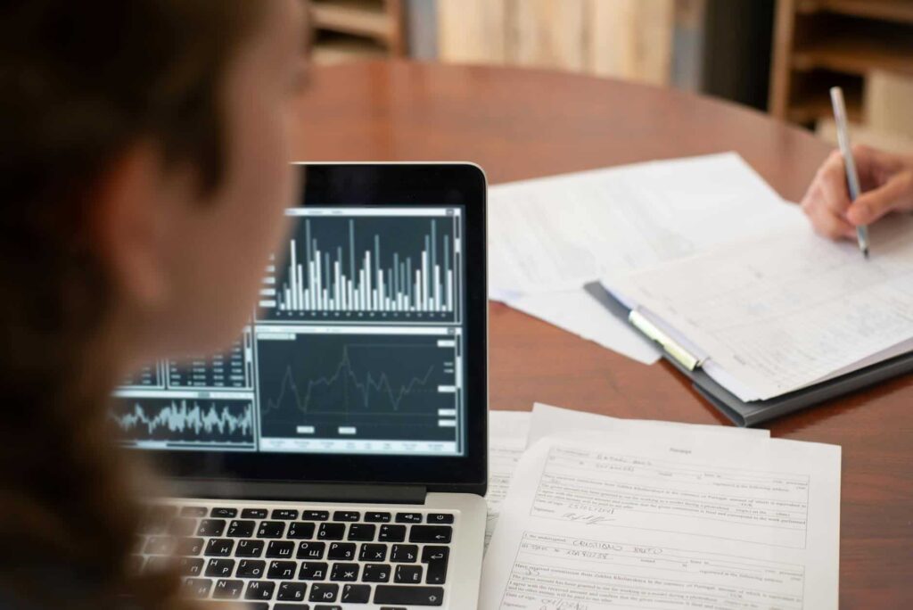 A woman is working on a laptop at a desk in the cybersecurity field.
